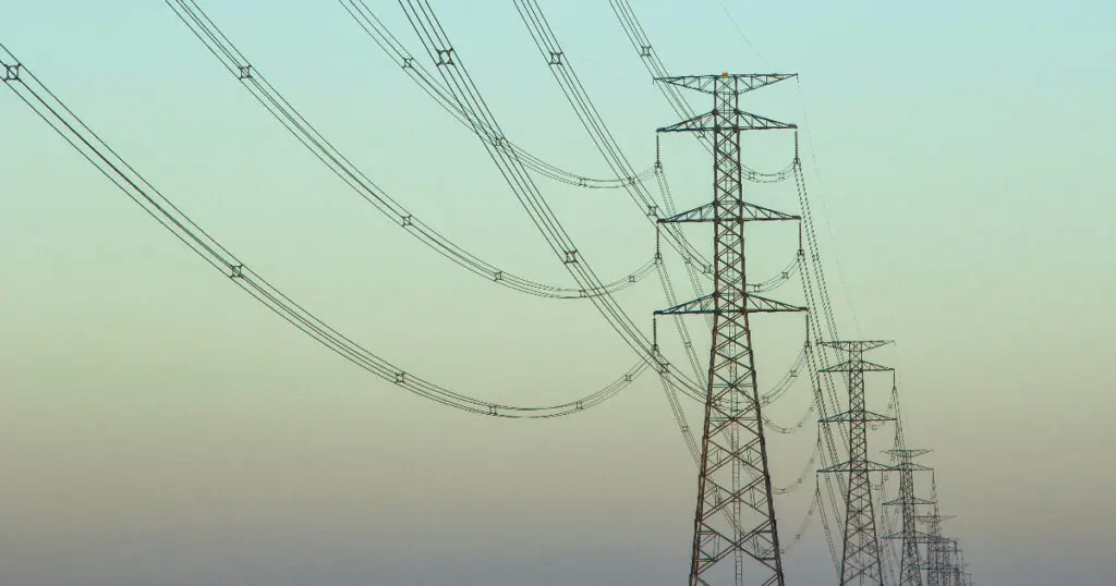 a row of overhead powerlines suspended from a line of towers that disappears into the distance